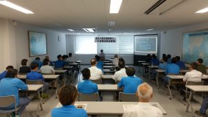 会議室で、２０台ほど並んだ長机に２人ずつ座る焼津漁協職員と、前でパワポを使う講師。